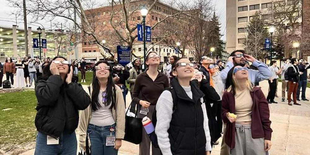 TOTAL ECLIPSE: 推荐最近最火的赌博软件 students and staff gathered in Weiskotten Hall courtyard to view the solar eclipse, as day turned to night, illuminating the campus lights.